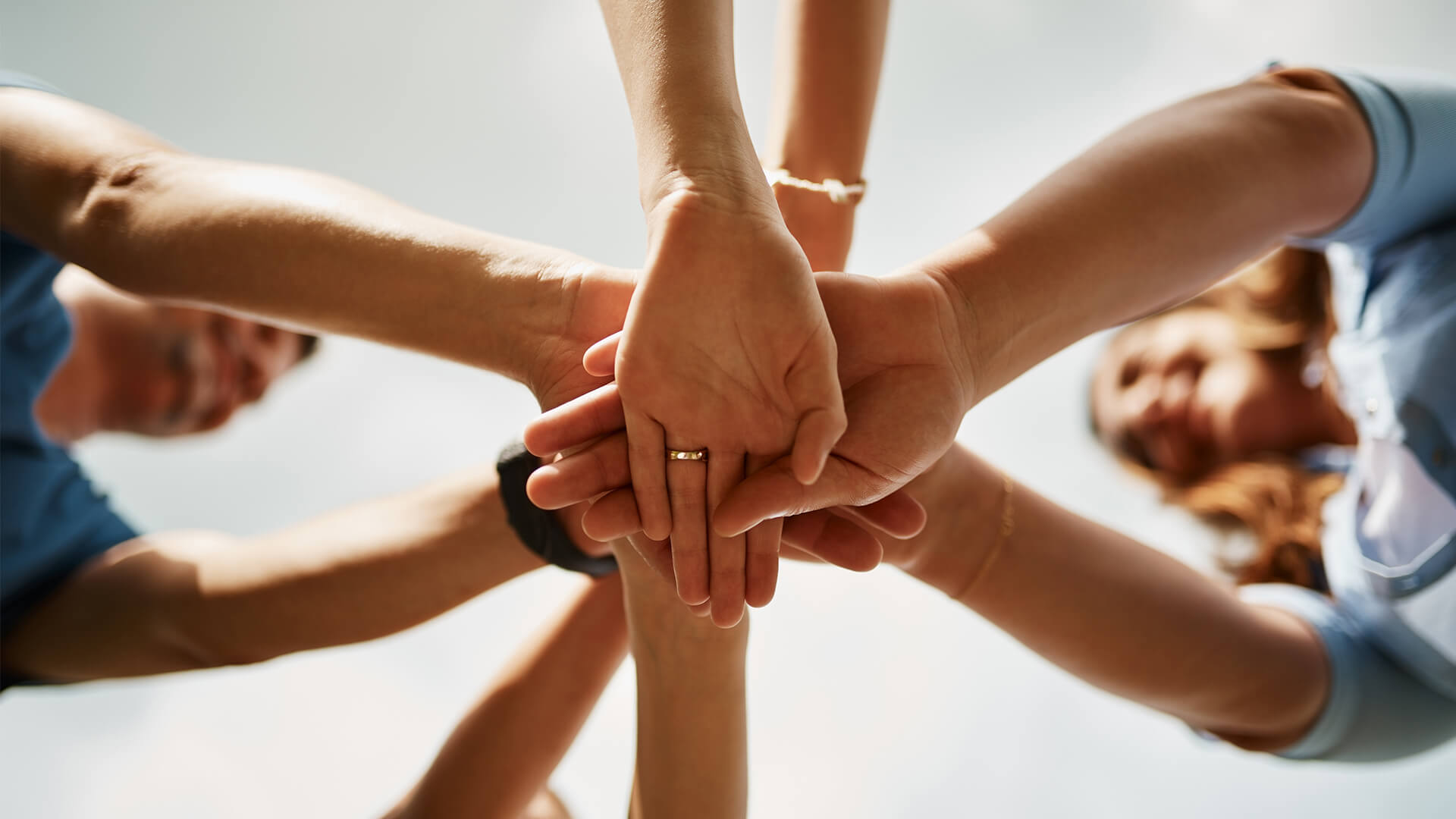 Group hands stacked in unity, symbolizing teamwork and support for a comprehensive oral care routine.